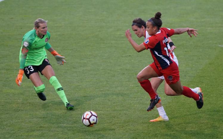 Women playing football and racing for the ball.