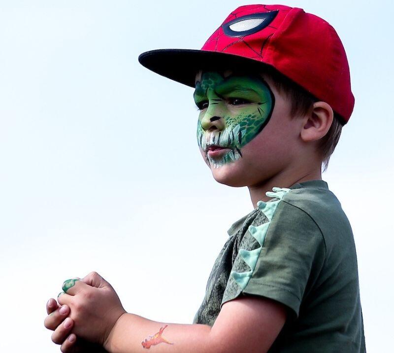 A little boy with his face painted at the races