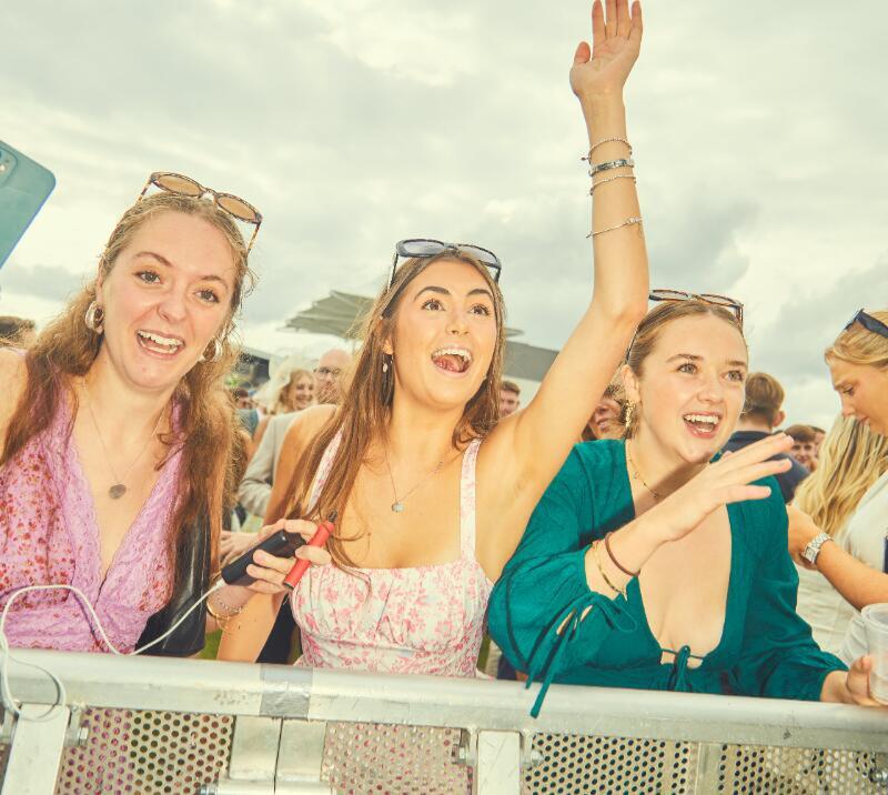 Three race goers dance to the live entertainment at Bath Racecourse