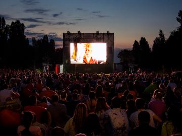 A crowd of people enjoying a movie at an outdoor cinema.
